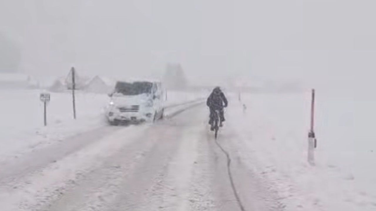 Kolesar v Pomurju vozi po zasneženi cesti med močnim sneženjem in zimskimi razmerami