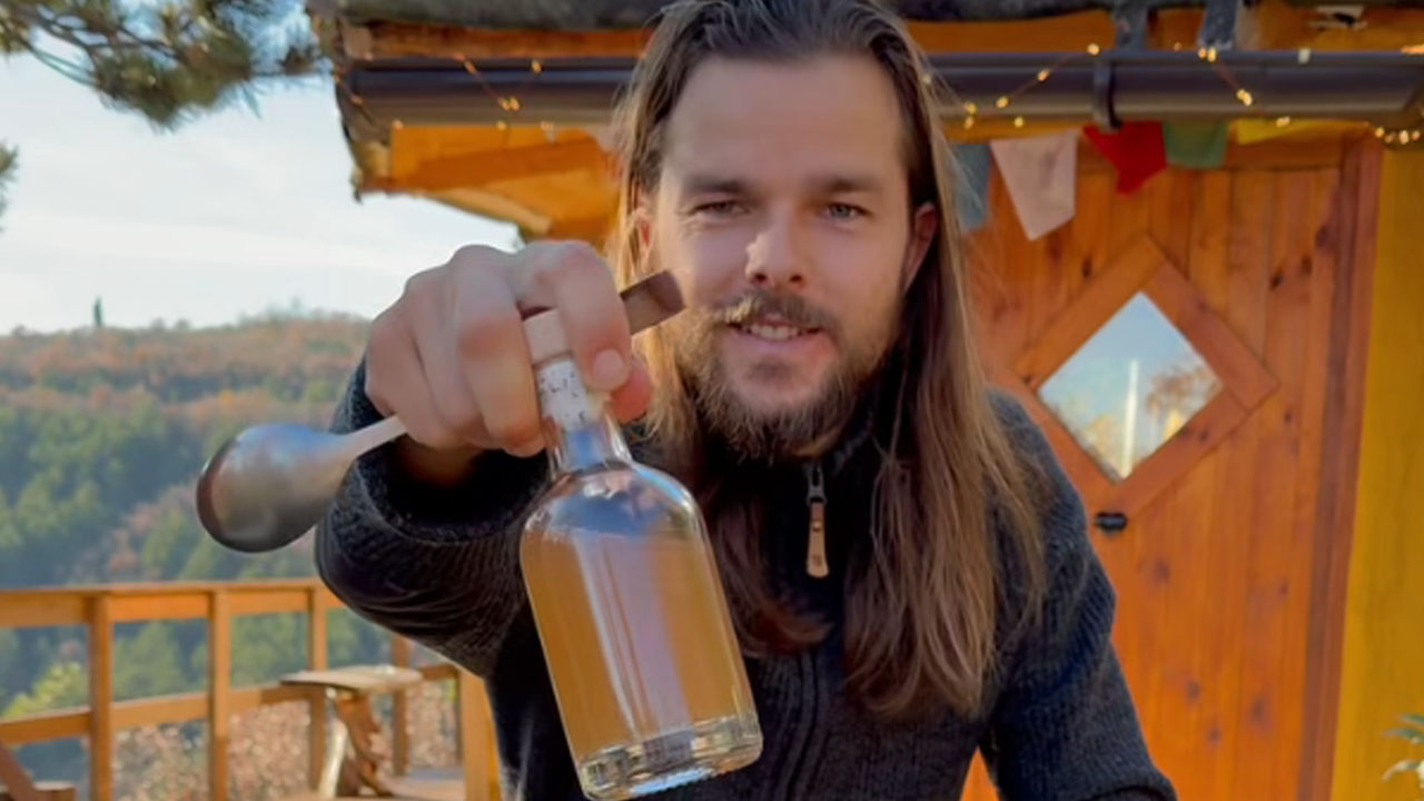Luka Lešnik v lesenem domu sredi gozda pripravlja domačo tinkturo za imunski sistem