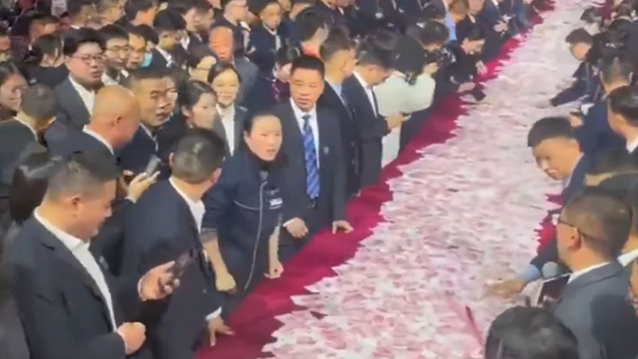 Zaposleni podjetja Henan Kuangshan Crane na gala večerji štejejo kupe gotovine na dolgih mizah