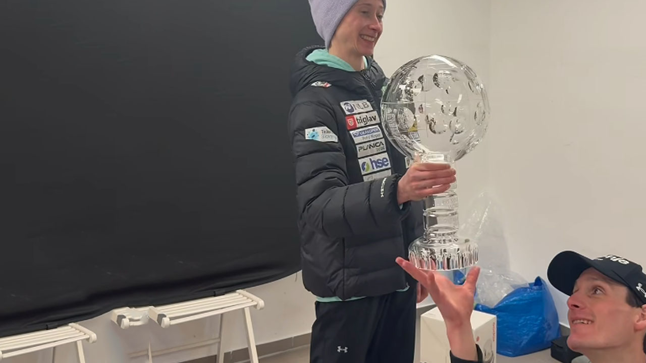 Domen Prevc pomaga Niki Prevc držati veliki kristalni globus v Planici po rekordni sezoni v smučarskih skokih