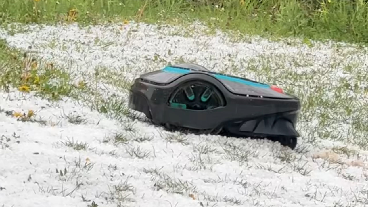 Robotska kosilnica obstane na travniku, prekritem s sodro med nevihto