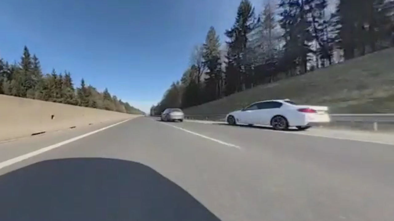 Posnetek belega BMW-ja, ki pri veliki hitrosti prehiteva kolono vozil po odstavnem pasu na slovenski avtocesti