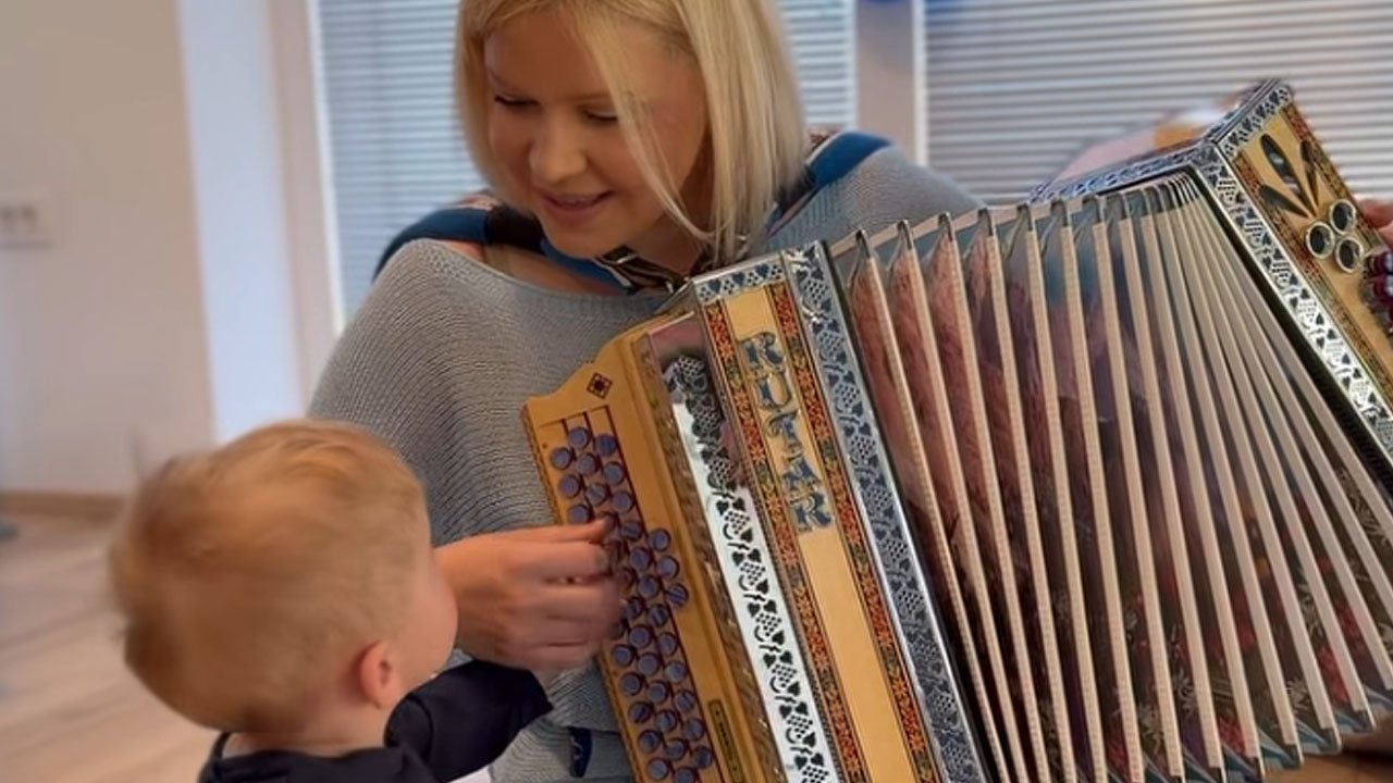 Darja Gajšek s harmoniko v naročju poje sinu Maju za njegov 1. rojstni dan