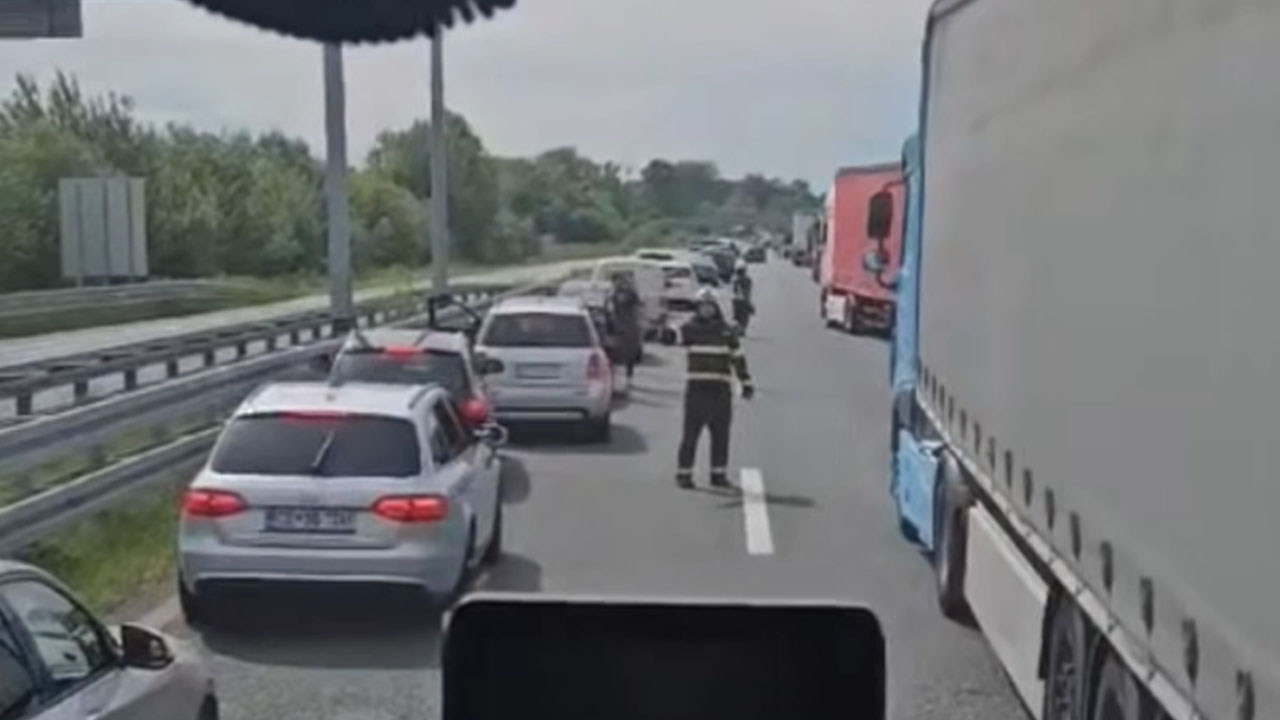 Gasilci v zaščitnih oblekah tečejo po avtocesti A3 med ustavljenimi vozili in z rokami nakazujejo smer umikanja