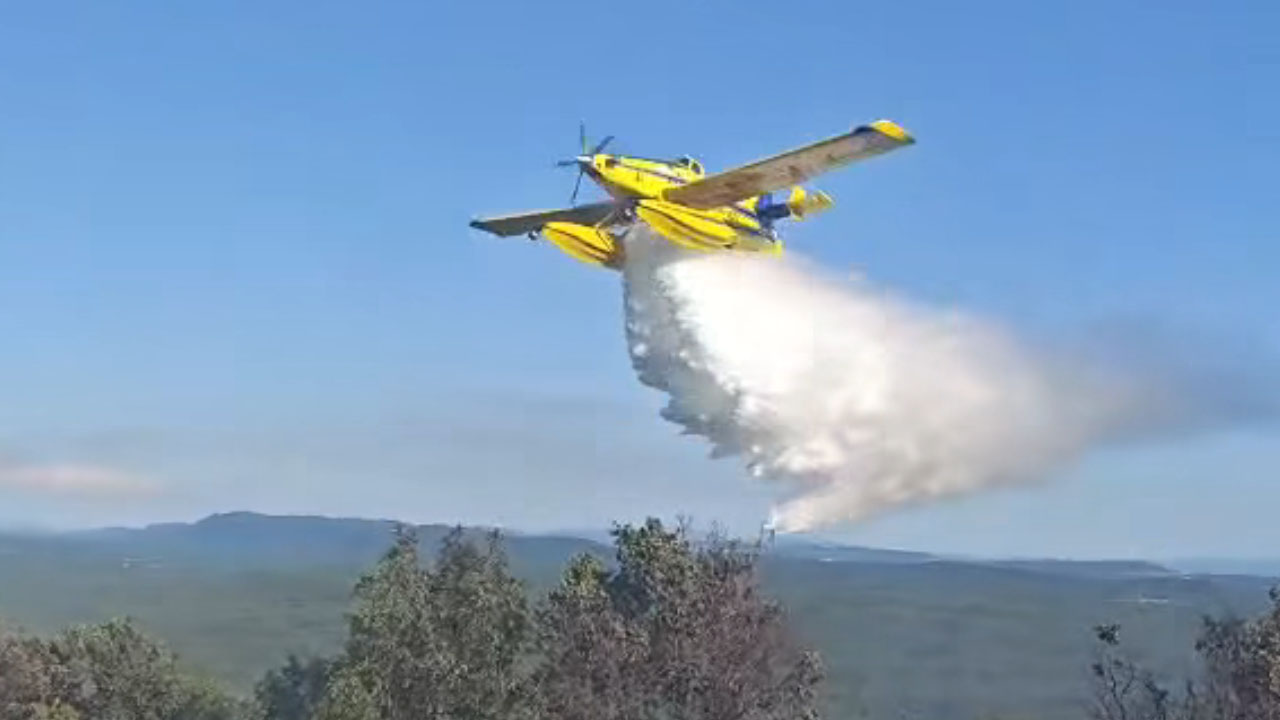 Letalo Air Tractor med gašenjem požara pri Brestovici pri Komnu iz zraka odvrže vodo tik nad gasilcem