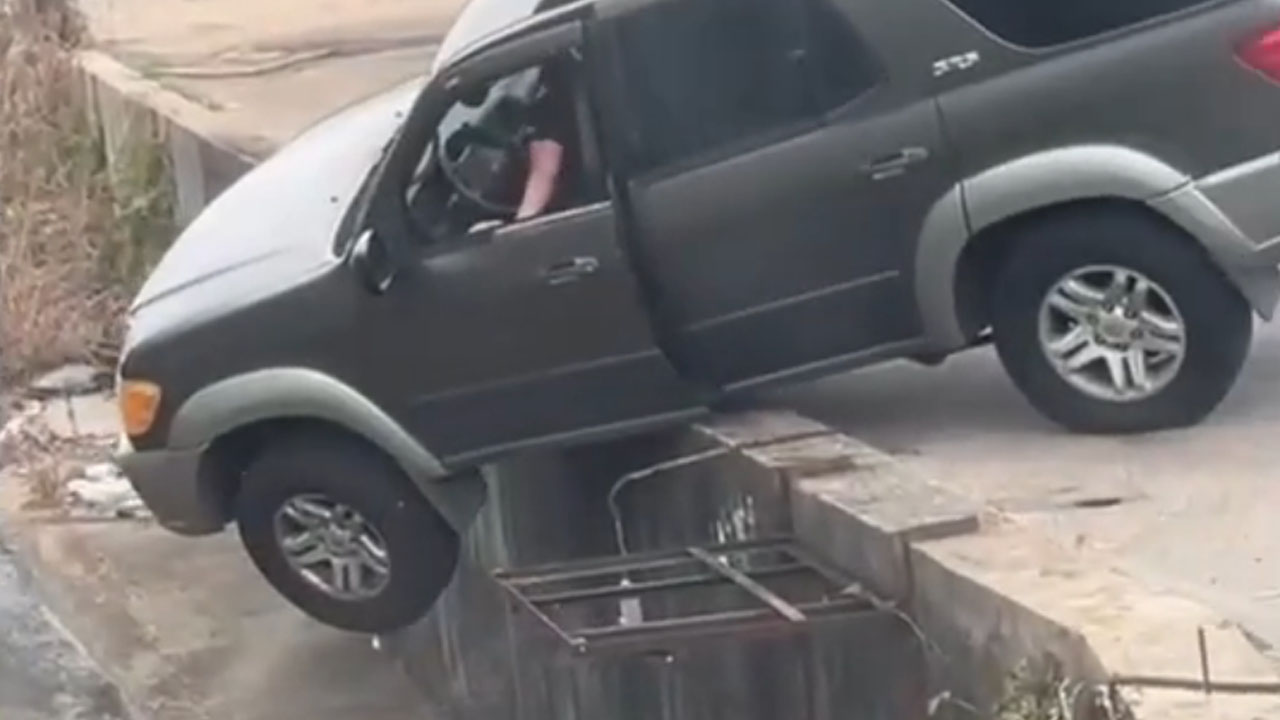 Toyota hanging over the edge of a wall before overturning into a drainage ditch