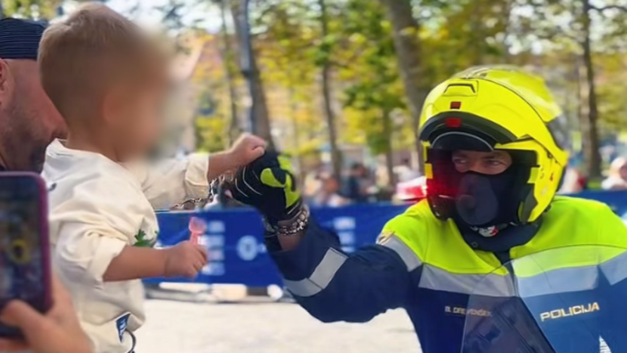 Slovenski policist na motorju med pozdravom malčka
